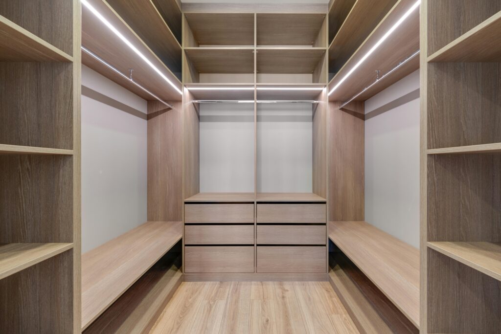 Spacious walk-in closet with wooden shelves and LED lighting creates a minimalist and modern design.