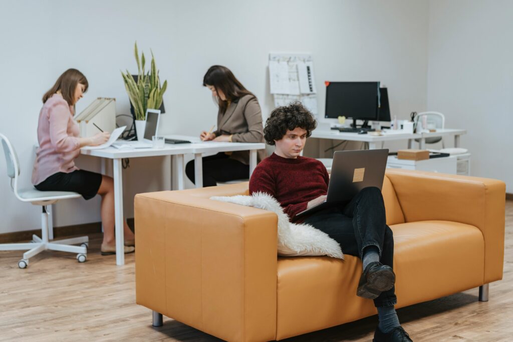People collaborating in a modern office space with laptops and documents.