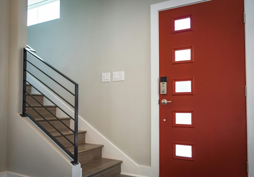 Contemporary interior with a vibrant red entrance door and stairs, showcasing minimalist design.